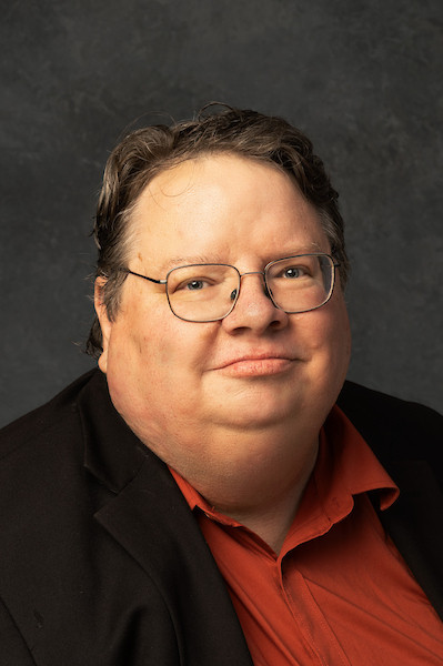 man with black jack on and tan top