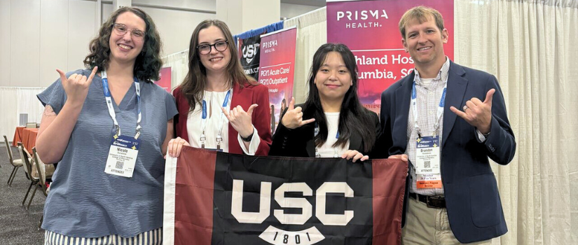 Students with faculty members holding USC Pharmacy flag