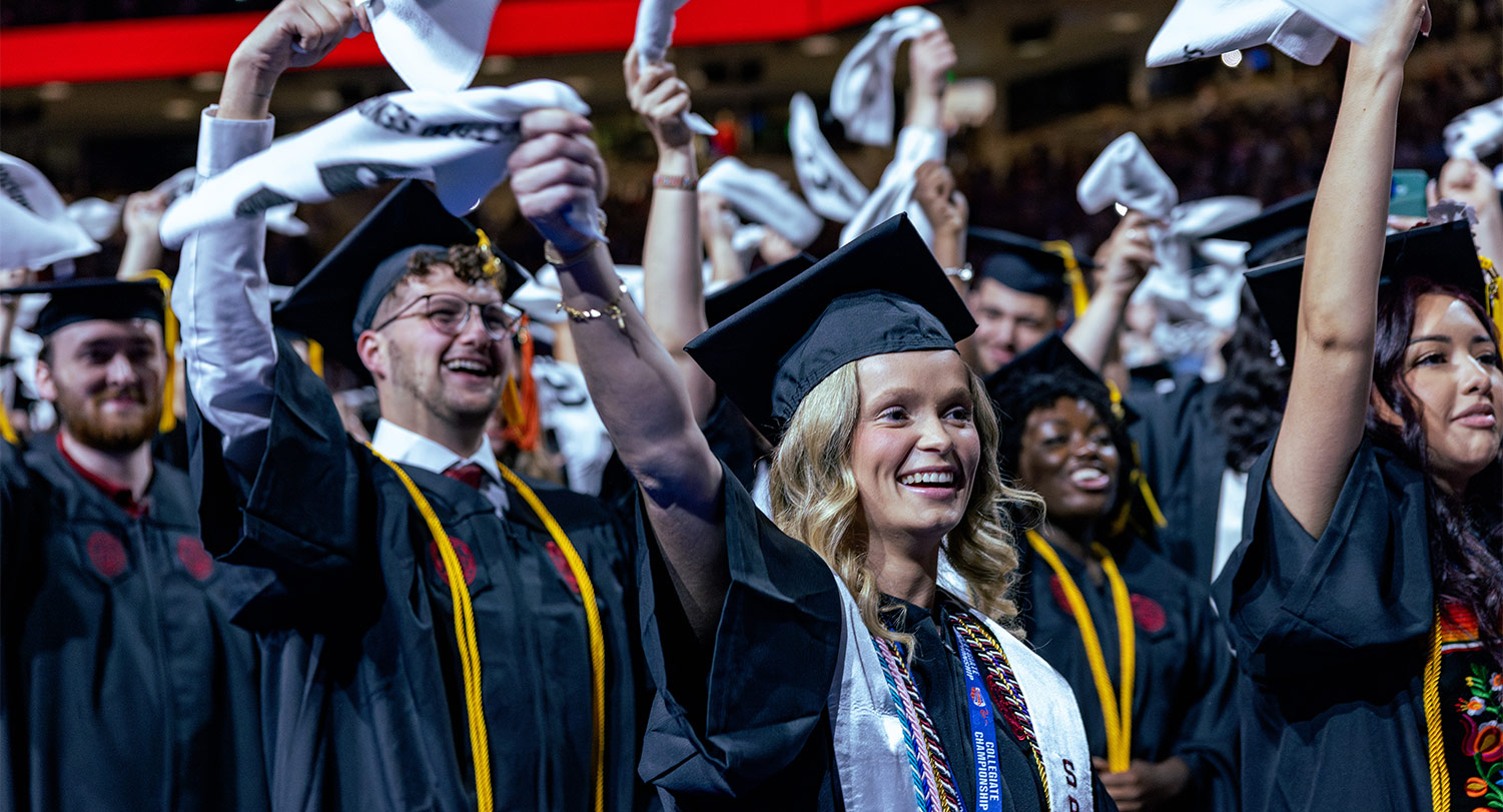 students at commencement waving white towels
