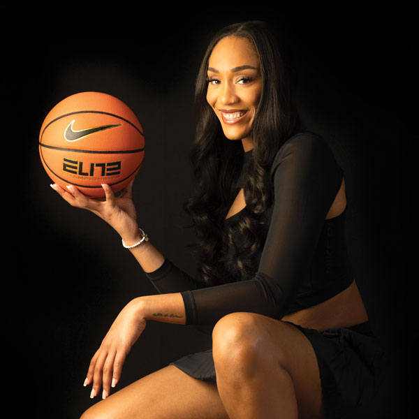 Aja Wilson smiles for the camera on a black background.