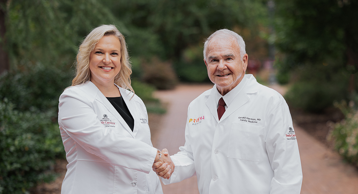 Dr. Phyllis MacGilvray and Dr. Gerald Harmon shake hands on USC's Columbia campus.